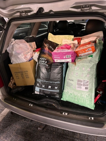Een autokofferbak is gevuld met verschillende zakken met dierenvoer, waaronder puppylam & aardappelen, kittenvoer en andere dierenbenodigdheden. Sommige artikelen worden bewaard in kartonnen dozen en plastic zakken. De kofferbak is tot de nok toe volgepakt, wat duidt op een grote donatie van dierenbenodigdheden. Een autokofferbak is gevuld met verschillende zakken met dierenvoer, waaronder puppylam & aardappelen, kittenvoer en andere dierenbenodigdheden. Sommige artikelen worden bewaard in kartonnen dozen en plastic zakken. De kofferbak is tot de nok toe volgepakt, wat duidt op een grote donatie van dierenbenodigdheden.